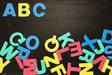 Alphabet magnets in a jumble on blackboard with Abc in order