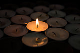 Single candle lighting surrounded by others