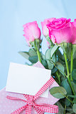 Bouquet of pink roses in vase with pink gift and blank card