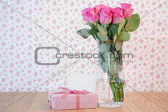 Bunch of pink roses in vase with pink gift and blank card
