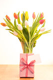 Vase of tulips on wooden table with gift and blank card