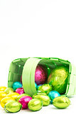 Foil wrapped easter eggs spilling from a basket