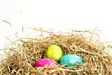 Three easter eggs nestled in straw nest