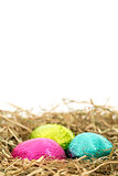Three foil wrapped easter eggs nestled in straw nest