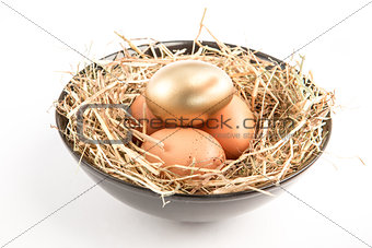 Three eggs in a black bowl with one gold one