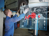 Mechanic checking wheel of a car helped by interface