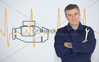 Mature mechanic standing in front of an engine background