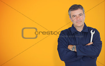 Mature mechanic standing in front of yellow background