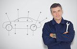 Mature mechanic standing next to car diagram