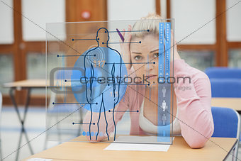 Blonde woman thinking hard while studying on interface with body