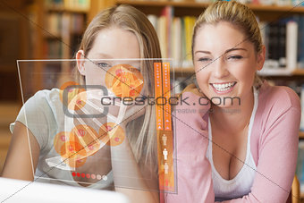 Two smiling students looking at laptop and futuristic interface
