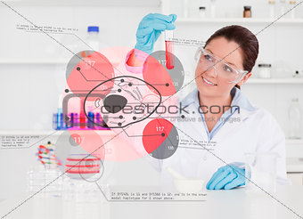 Smiling chemist looking at test tube of red chemical
