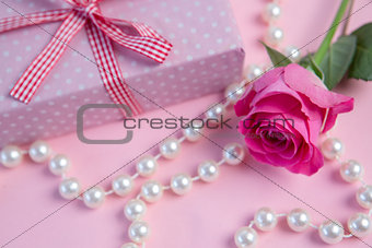 Pink rose with gift and string of pearls