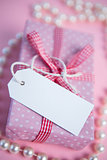 Pink gift wrapped box with blank tag and pearls