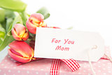 Bouquet of tulips next to a gift with a card for a mother
