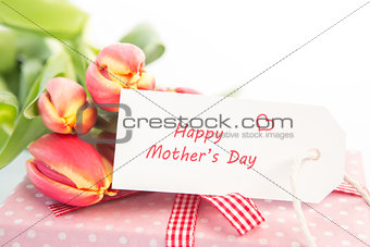 Bouquet of tulips next to a gift with a happy mothers day card