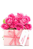 Bouquet of beautiful pink roses next to a pink gift with a happy mothers day card on white backgroun