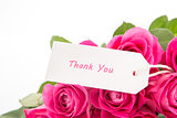 Close up of a beautiful bouquet of pink roses with a thank you card on a white background