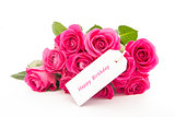 Close up of a beautiful bouquet of pink roses with a happy birthday card on a white background