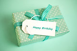 Pretty green gift with a happy birthday card on a green background
