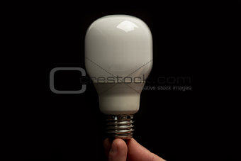Man holding economic light bulb in his fingertips close up