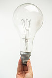 Man holding big light bulb at his fingertips close up