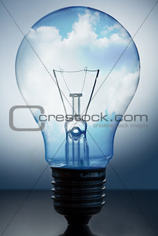 Close up of big light bulb standing with bright blue sky in it