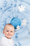 Portrait of a baby with globe and jigsaw pieces background