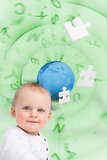 Portrait of a baby with planet and jigsaw pieces green background