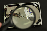 Hand holding magnifying glass over disk drive