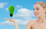 Smiling woman looking at green light bulb
