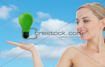Smiling woman looking at green light bulb