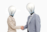 Business people with lightbulb heads greeting with a handshake