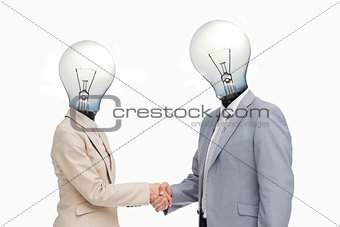 Business people with lightbulb heads greeting with a handshake