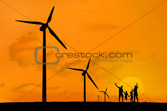 Wind turbines and family jumping with a sunset