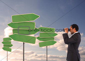 Businessman looking at empty signposts with binoculars