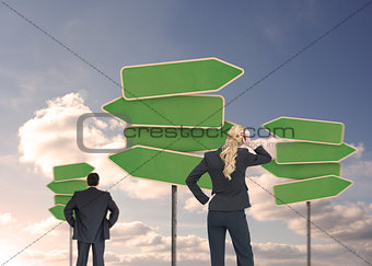 Rear view of businesspeople looking at empty signposts