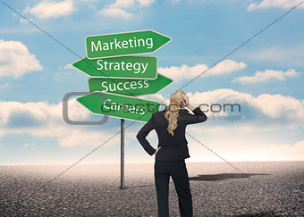 Businesswoman looking at signposts with marketing terms