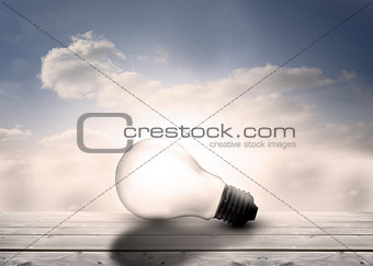 Light bulb resting on floorboards in the sky