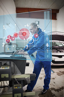 Mechanic typing while consulting futuristic interface with car diagram