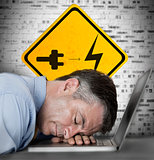 Businessman sleeping on his laptop with battery plug roadsign