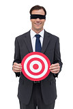 Blindfolded and smiling businessman holding a red target