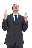 Businessman with fingers crossed is looking up
