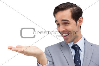 Smiling businessman looking at and showing his opened hand