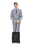 Serious businessman waiting with his suitcase
