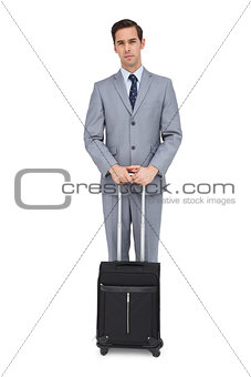 Serious businessman waiting with his suitcase