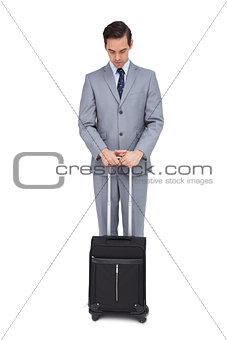 Serious young businessman waiting with his suitcase
