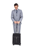 Smiling young businessman waiting with his suitcase