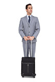 Serious young businessman waiting with his luggage