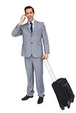 Smiling businessman with his luggage while phoning